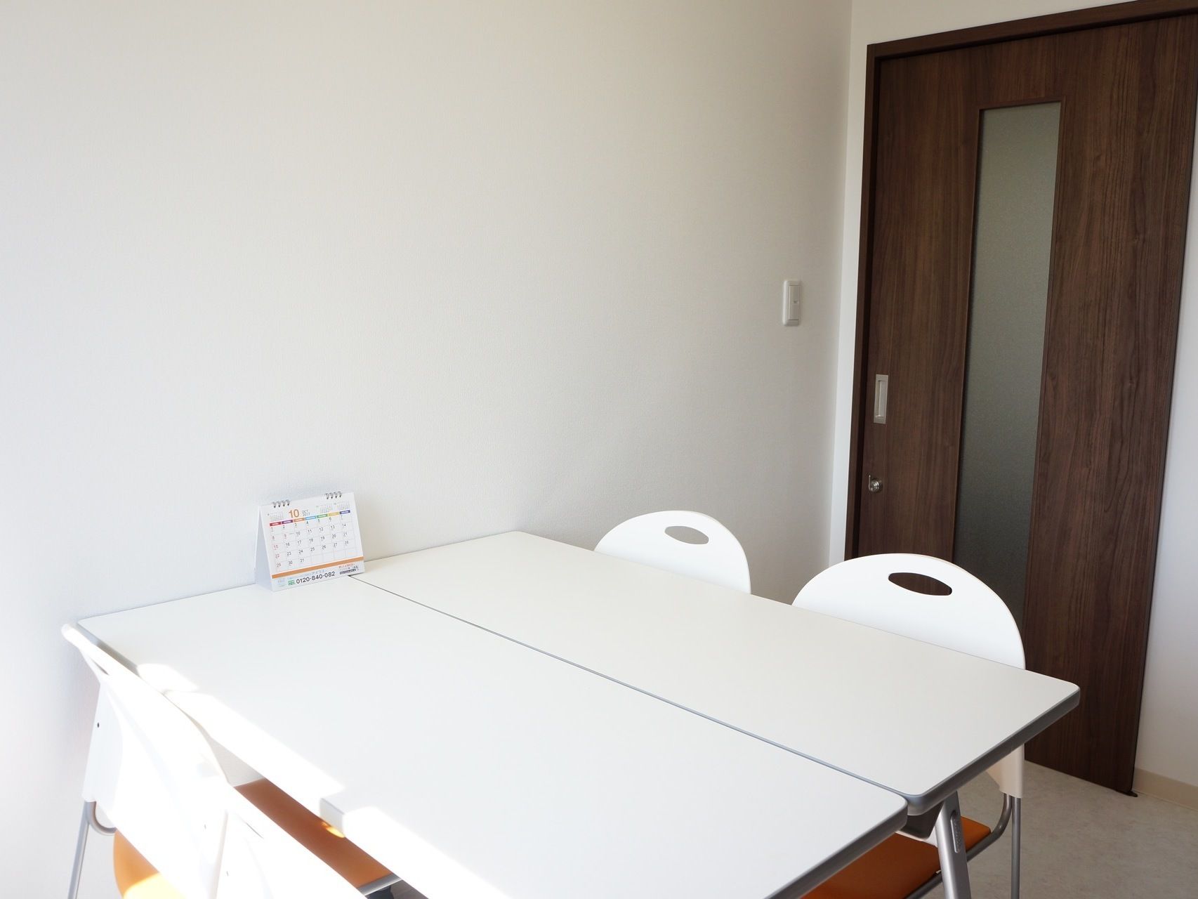 テーブル、椅子がある。扉はスライド式である。壁と家具が白でまとめられており、落ち着いた雰囲気となっている。