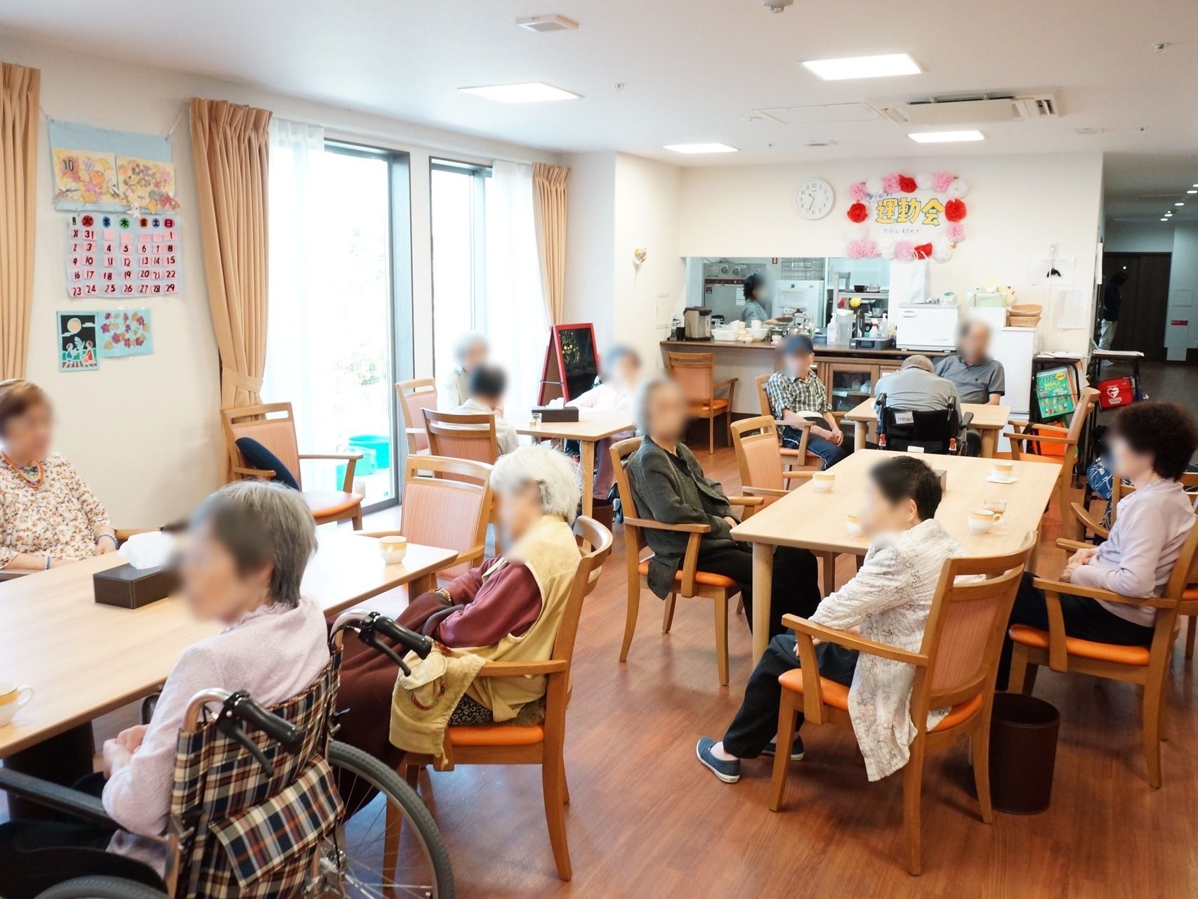 食堂のテーブルに着き、他の入居者たちと会話を楽しむ高齢者たち