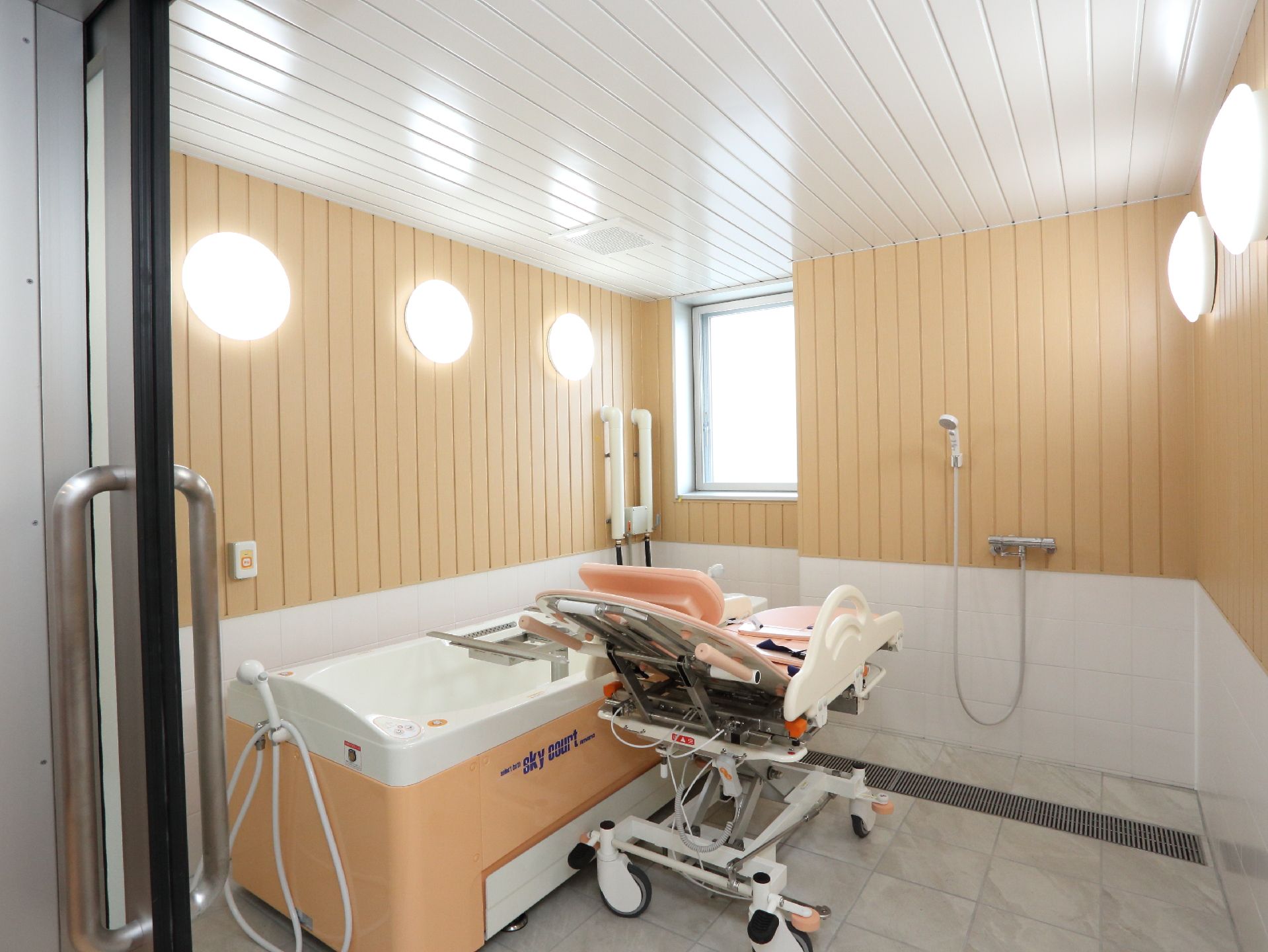介護用器具が置かれている浴室内はたくさんの電灯がついており、広めでありながら全体的に明るくなっている。