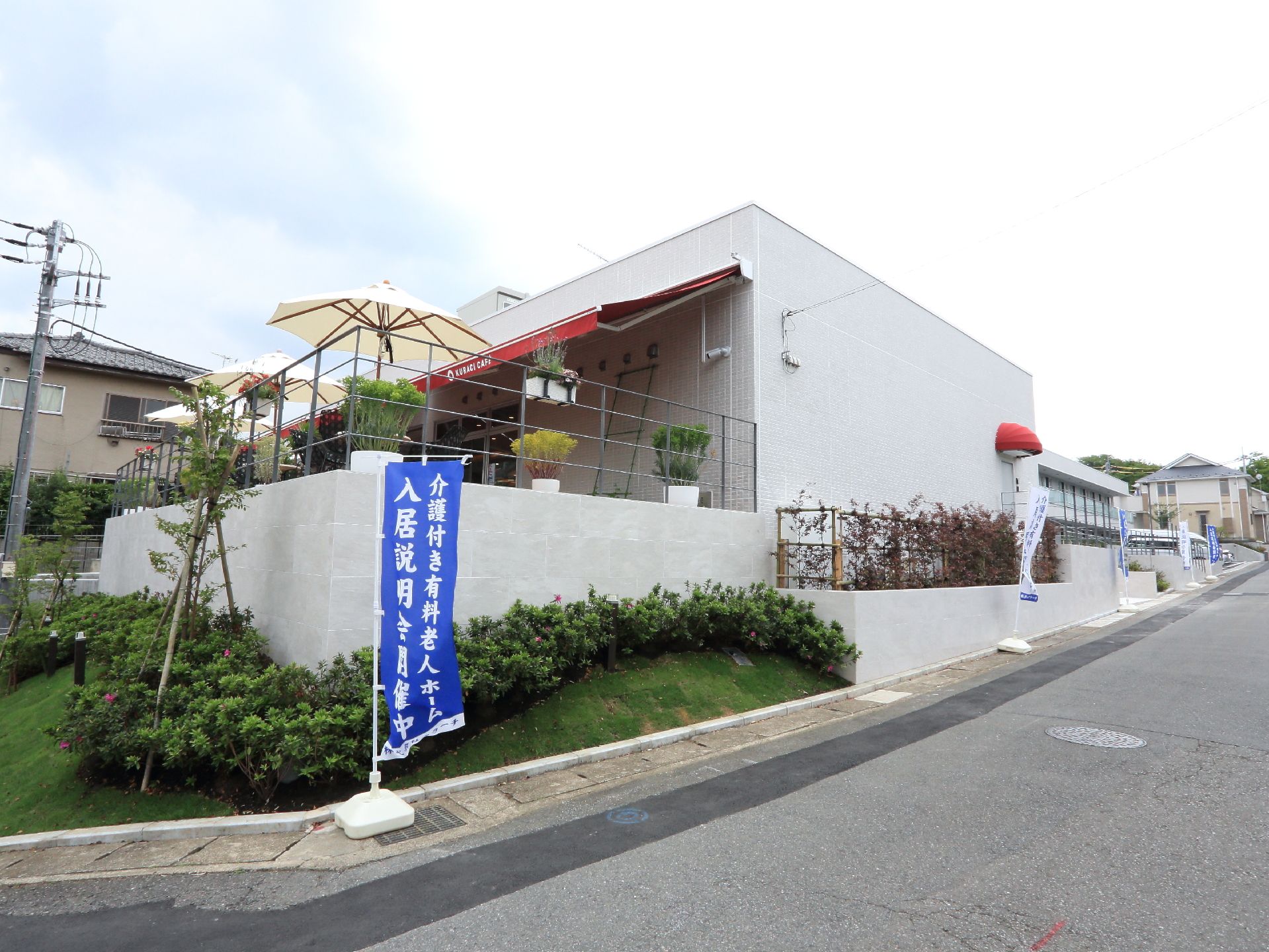 施設を横から見ると、やや坂になっている部分には緑が生い茂っており、2階部分には観葉植物やパラソルを見ることができる。