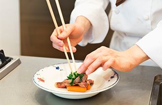 箸でお皿に料理を盛り付ける様子