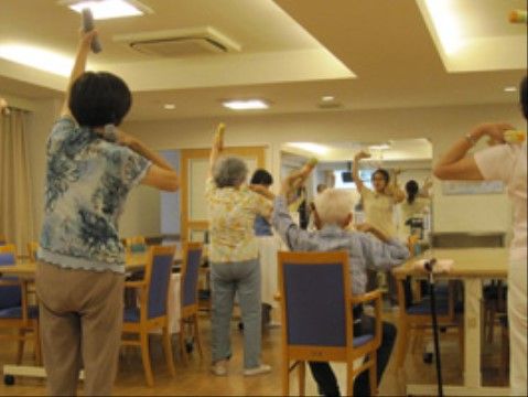 施設の職員とともに手を上げ健康体操をする高齢者たち