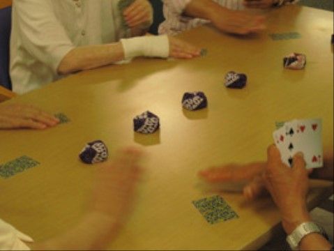 四角いテーブルを囲み、お手玉やトランプで遊ぶ入居者たち