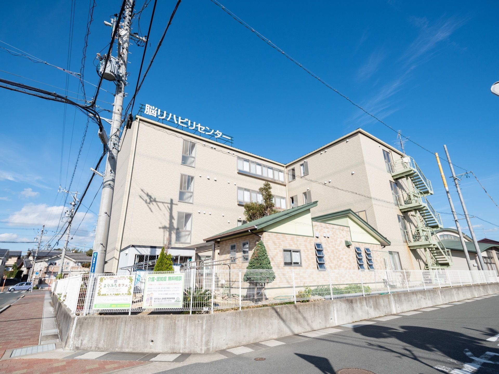 3階建ての建物の上に、脳リハビリセンターの看板がある。その1、2階を利用した認知症改善と予防に特化した施設である。周辺は落ち着いた市街地。