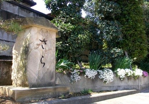植物の植え込みの脇に置かれた文字の刻まれた石のオブジェ