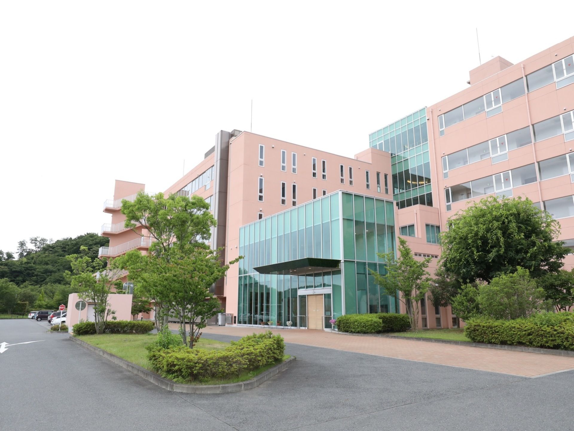 施設は、茶色い外壁とガラス張りの窓で統一された大きな建物となっている。敷地内には、木や植物がたくさん植えられている。
