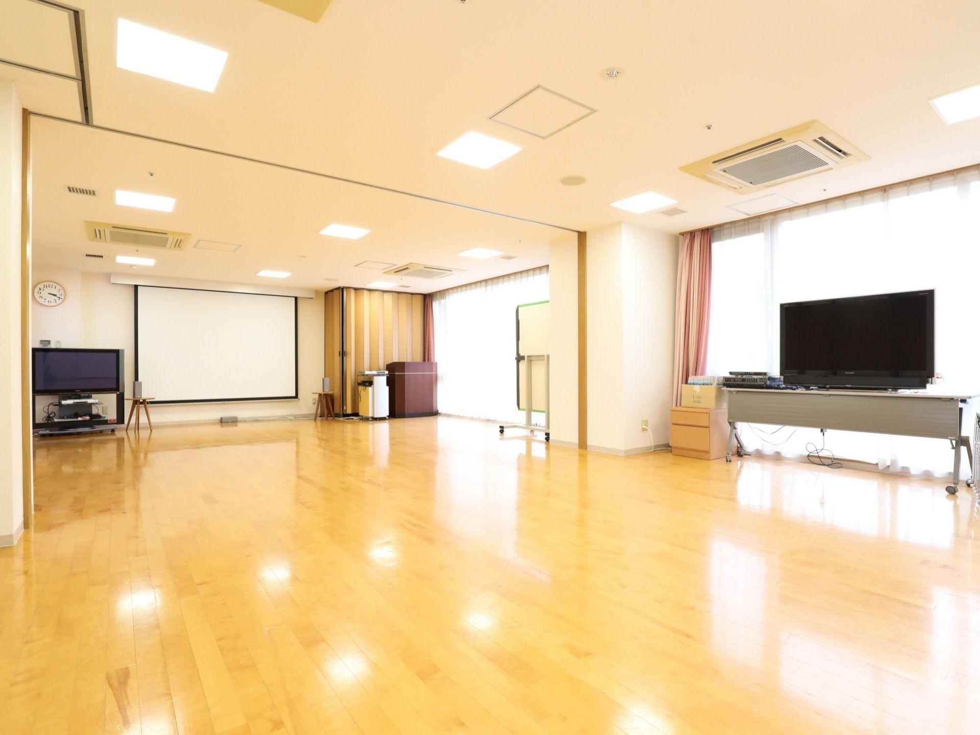 共有スペースは広々としており、全面がフローリングの床となっている。室内には大きなテレビが2台あり、スクリーンも掛けられている。