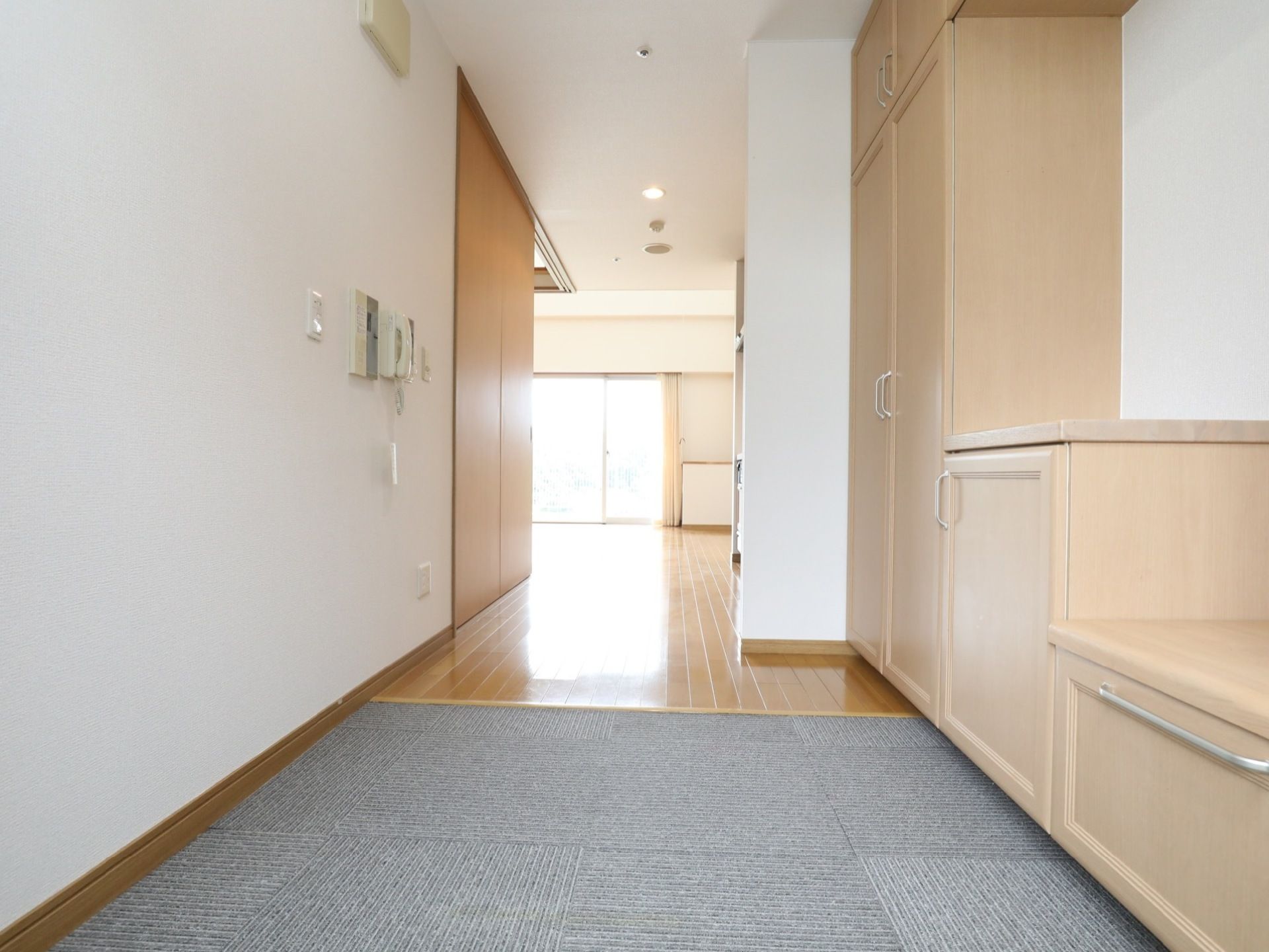 玄関部分は絨毯が敷いてあり、部屋はフローリングになっている。奥のほうには窓があり、光が差し込んでいる。