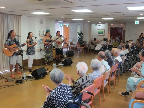 ギターやウクレレを持ち歌うパフォーマンスを見守る入居者たち