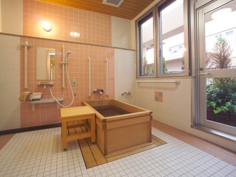 木の椅子や浴槽がある浴室には、ゆとりをもってつくられた洗い場もあり、窓辺からは外の緑の木々が見え、ゆったりと入浴できる。