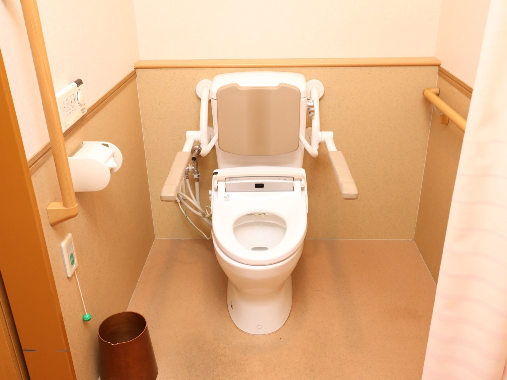 周りの壁は木製で温かみがある。手すりがあることで、高齢者の方でも安全に立ったり座ったりできる。介護者の方も入れる十分なスペースがある。