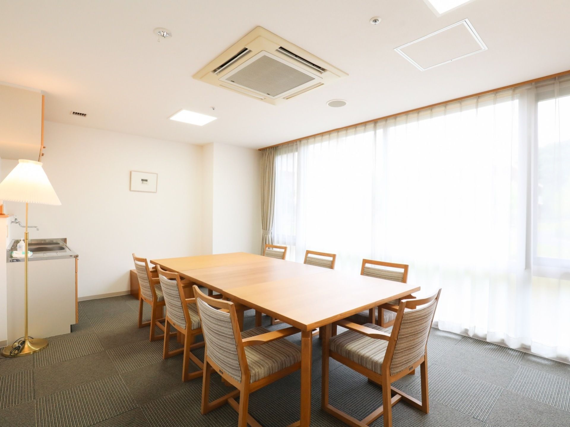 椅子が７脚と大きなテーブルがあり、談笑や会議に最適である。大きな窓から差し込む光で明るい室内になっている。