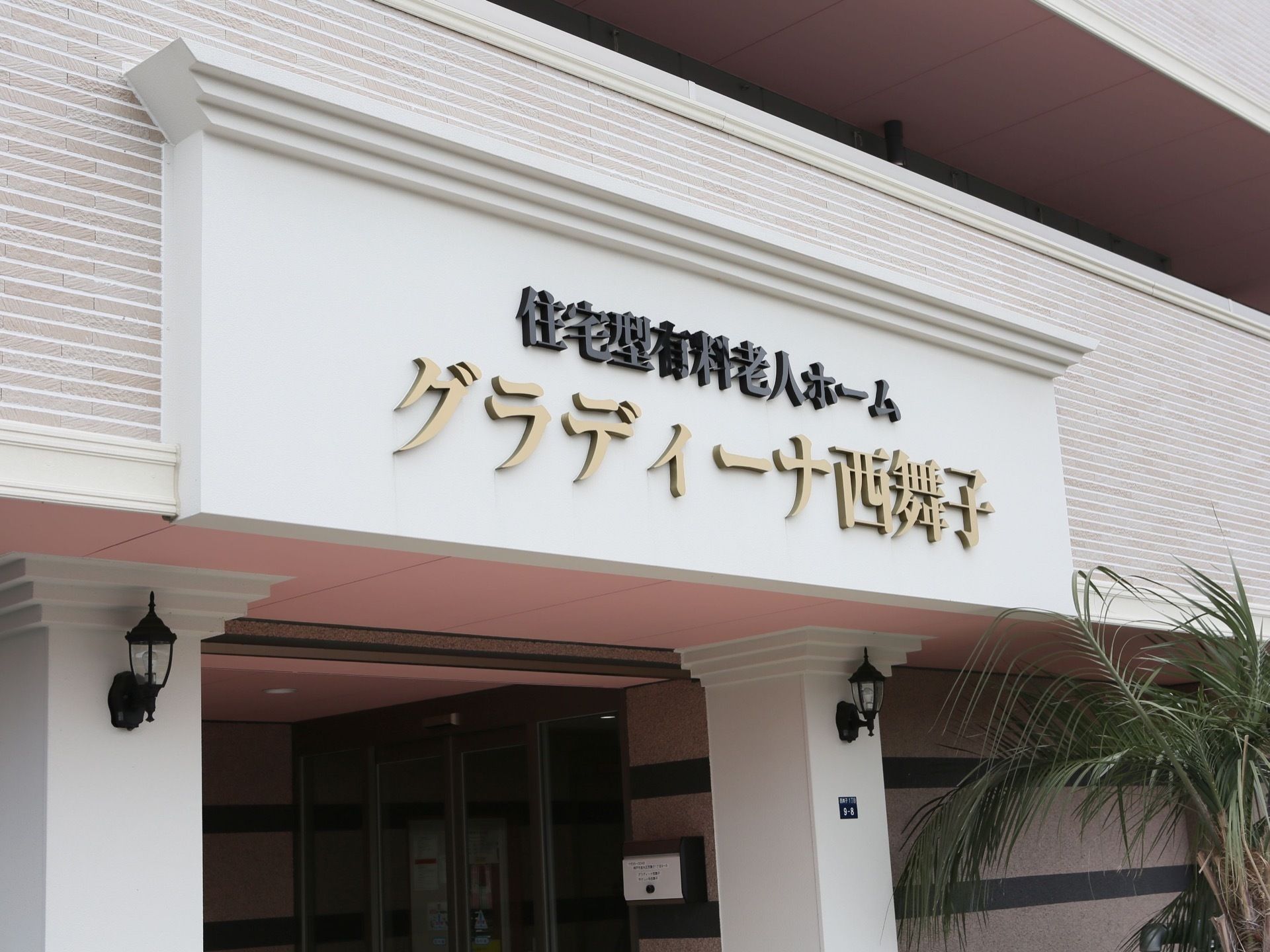 玄関前のスペースの屋根部分に、施設名を表示している。黒色とベージュで大きく書かれており、遠くからもみゃすくなっている。