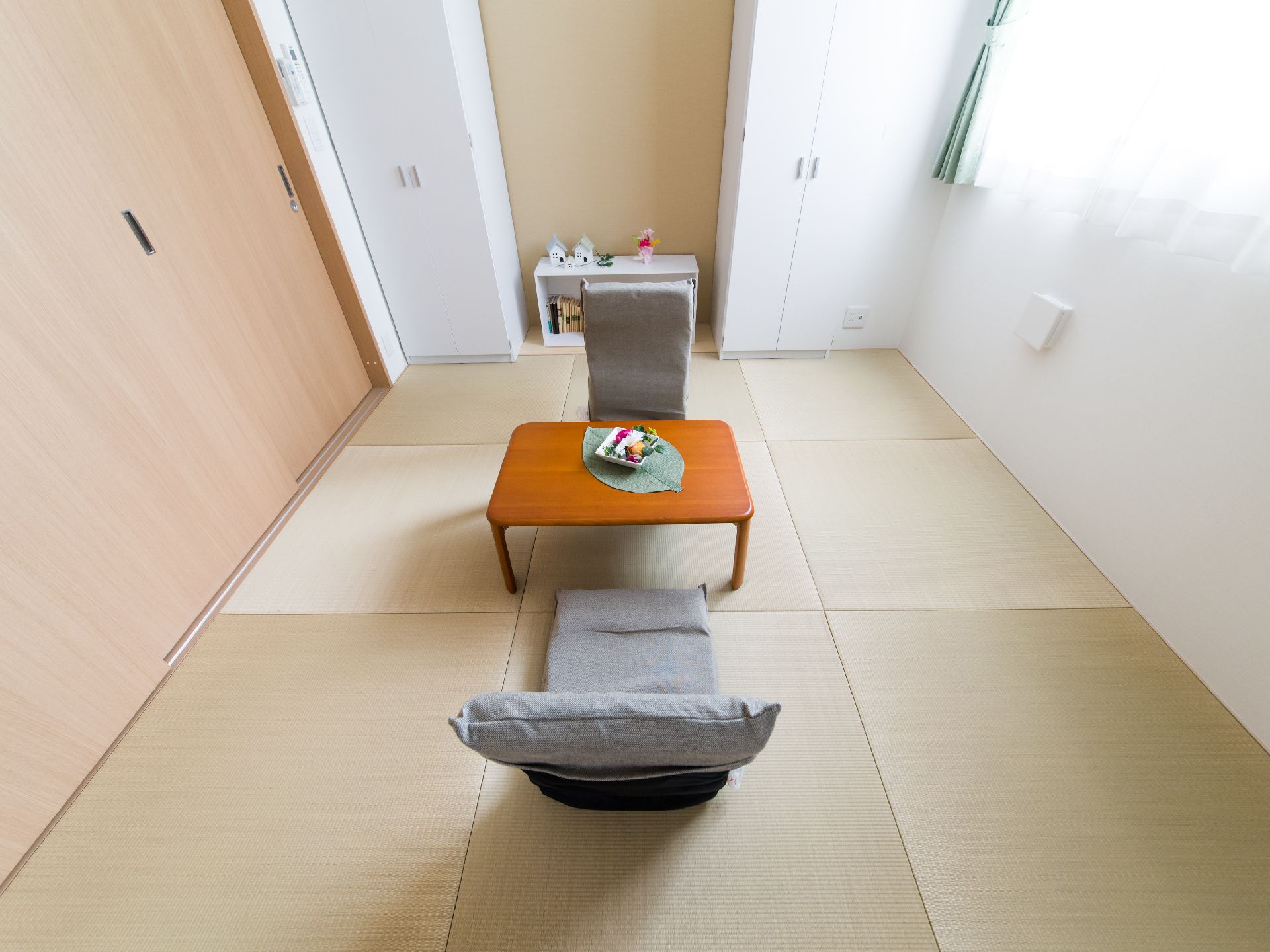 部屋の1方向には板敷きの部分があり、壁の両脇には白いクローゼットが1つずつ設置されている。中間部分には白い棚が置かれている。