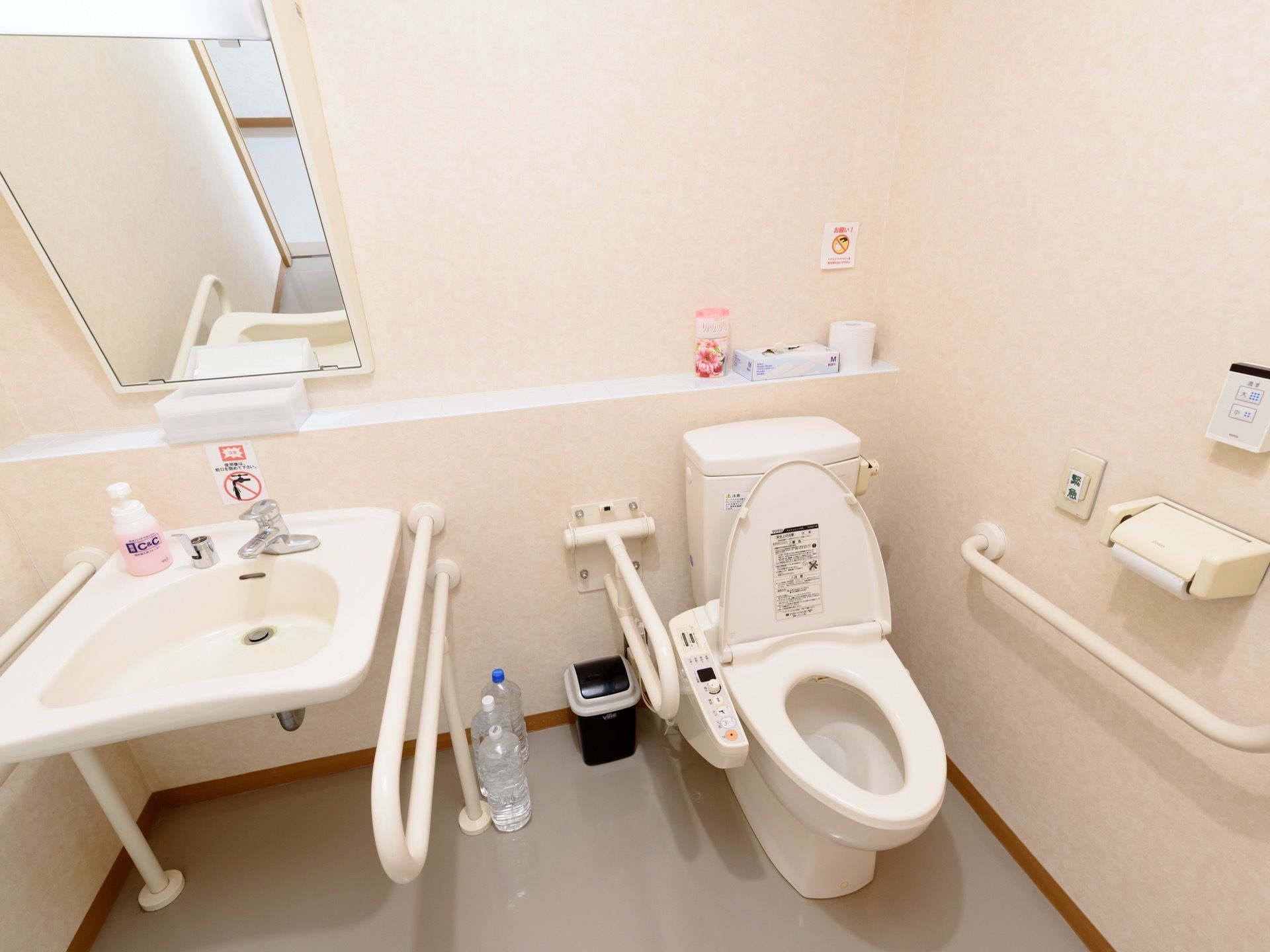 共用のトイレである。温水洗浄機能付き便座の隣には、フットレスタイプの洗面所が備わっている。手すりがどちらも両側に備わっている。