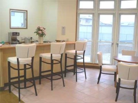 沢山の窓から外の見える部屋の、カウンターに並ぶ椅子とテーブル席