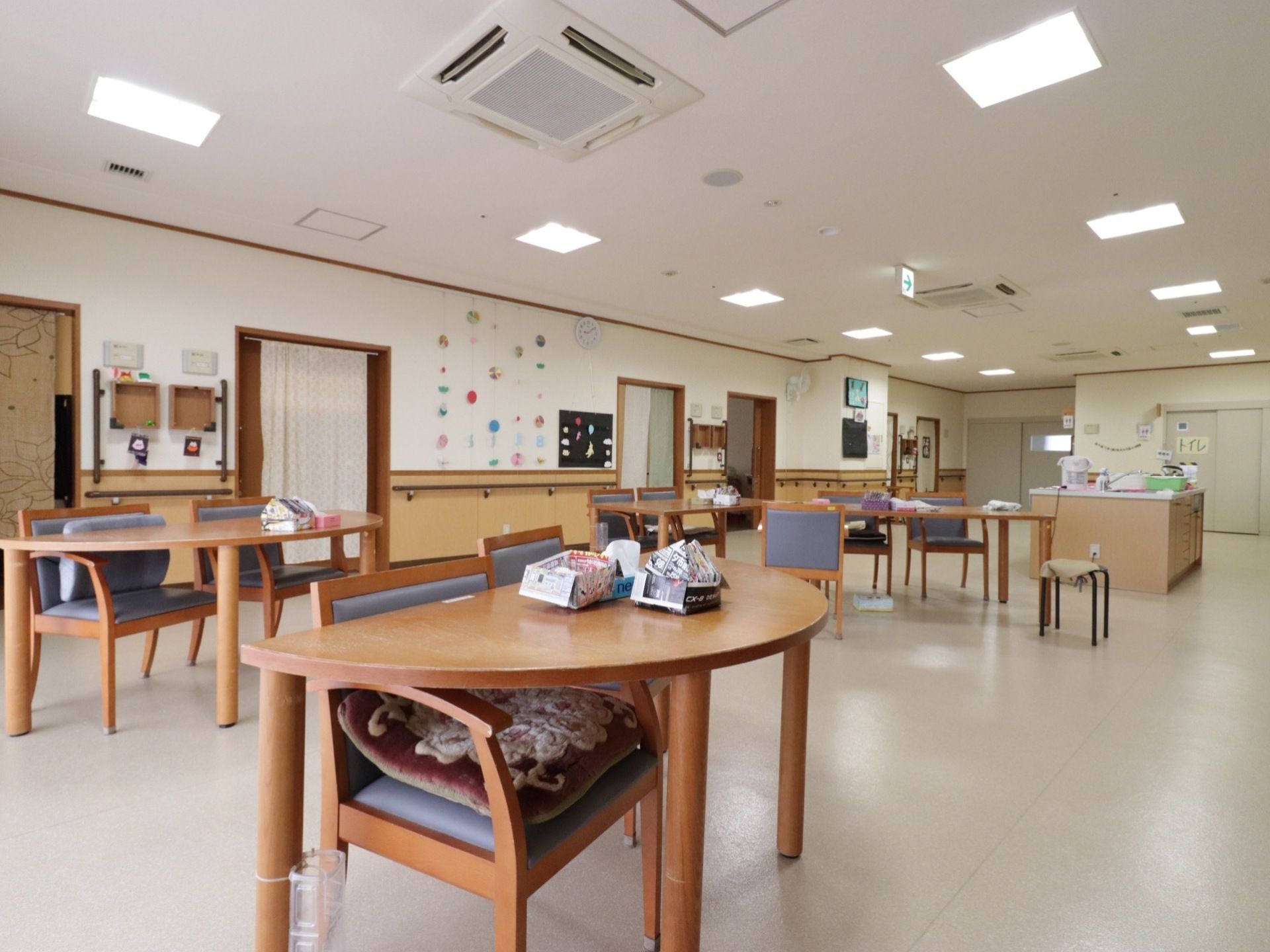 広い空間の食堂はテーブル間が空けられており、車椅子をご利用の方でも移動がしやすくなっている。壁には手すりが付いている。