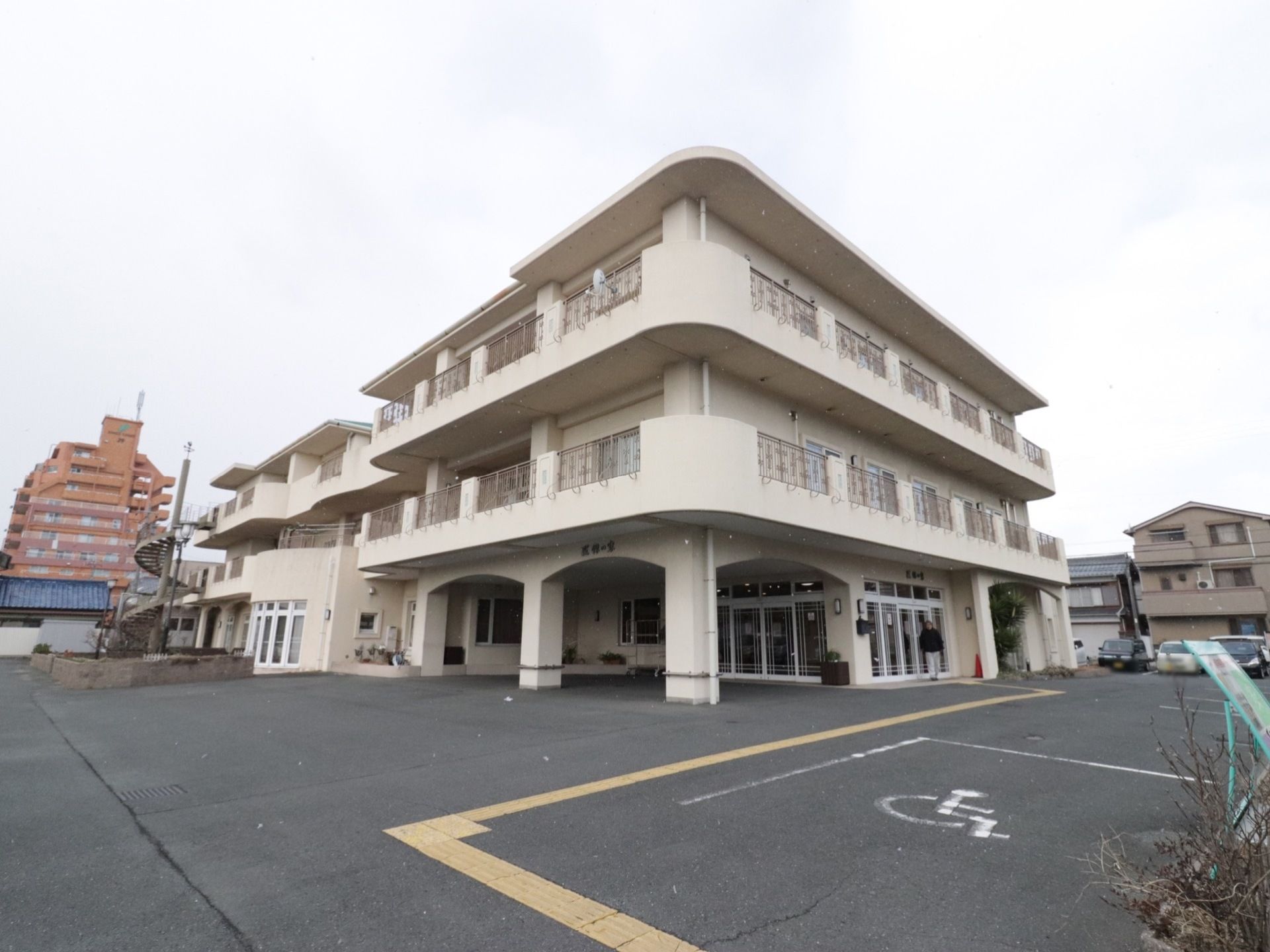 施設は白色の3階建ての建物になっており、駐車スペースも設けられている。玄関前は屋根部分が広く取られている。
