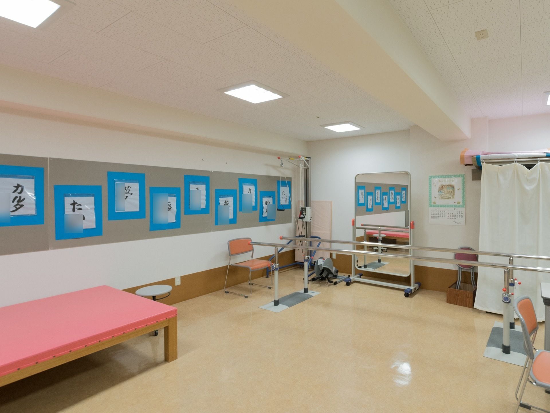 歩行訓練用の棒が２本あり、歩くリハビリができるようになっている。壁には、入居者様の習字が掛けられてある。