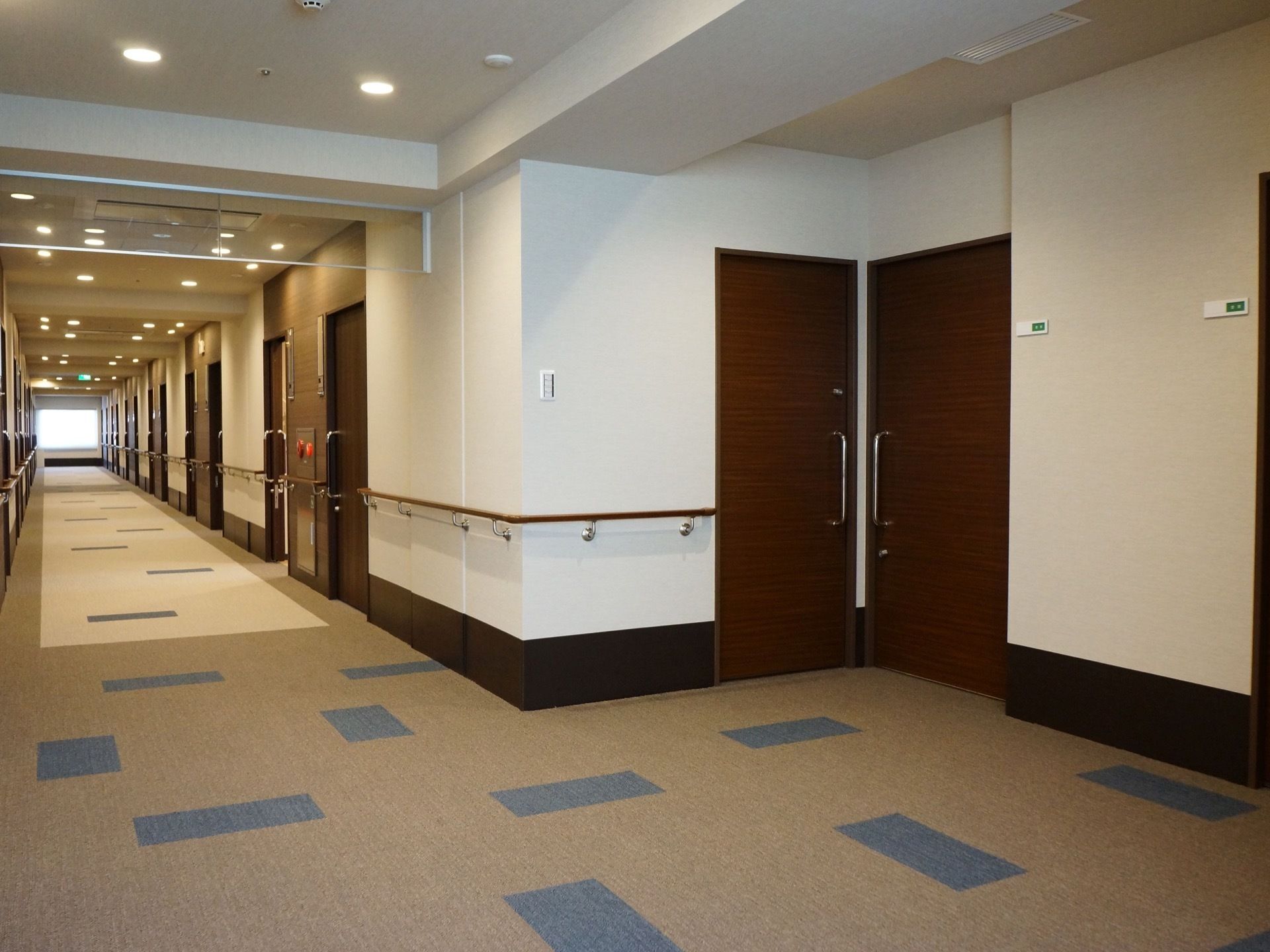 通路は白色の壁とシックなブラウンの引き戸が落ち着いた印象を与える。床はマットになっているので、すべりにくい。