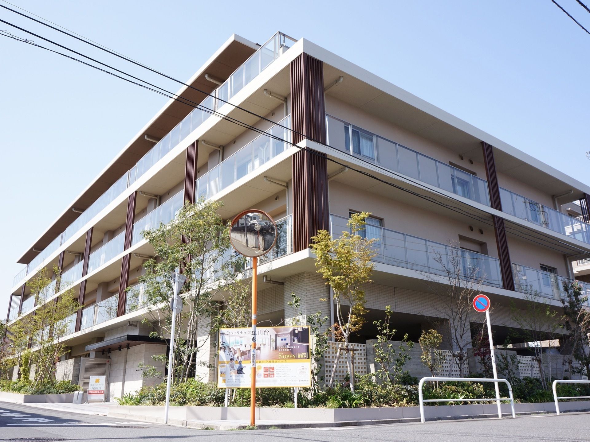 街路樹が並ぶ歩道の脇に建てられたベランダの広い部屋が並ぶ建物