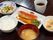 ご飯とお味噌汁。メインおかずの魚料理。いくつかの種類の野菜やエビ、椎茸などとあえて料理された小鉢が2つとお茶。一食のメニューである。