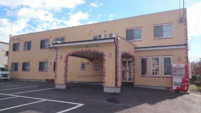 レンガで縁取りされた優しいオレンジ色の外壁の２階建の建物である。建物の前はアスファルトの駐車場になっている。