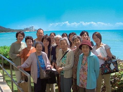 老若男女が、綺麗な海と青空を背景に、皆笑顔で映る集合写真