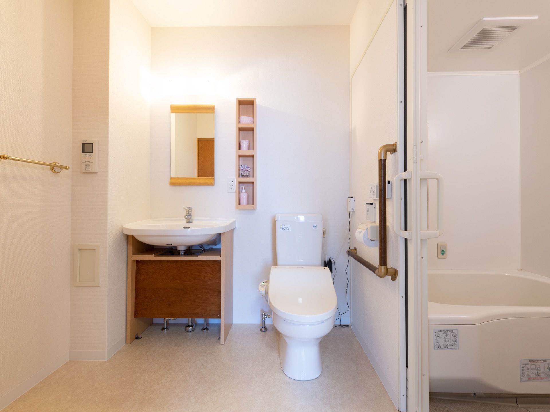 広々としたスペースにトイレと洗面台が設置されている。トイレの横にはＬ字型の手すりが取りつけられている。