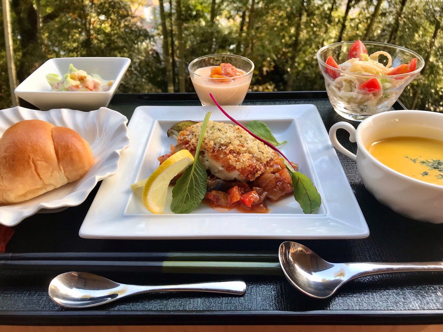 赤飯と焼き鮭、小鉢に盛られた野菜のおかずに箸とフォークが添えられている