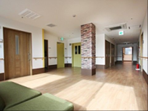 通路から続く場所にホールがある。エレベーターがあり、壁や中央の柱には手すりがつけられている。非常口の標識がある。