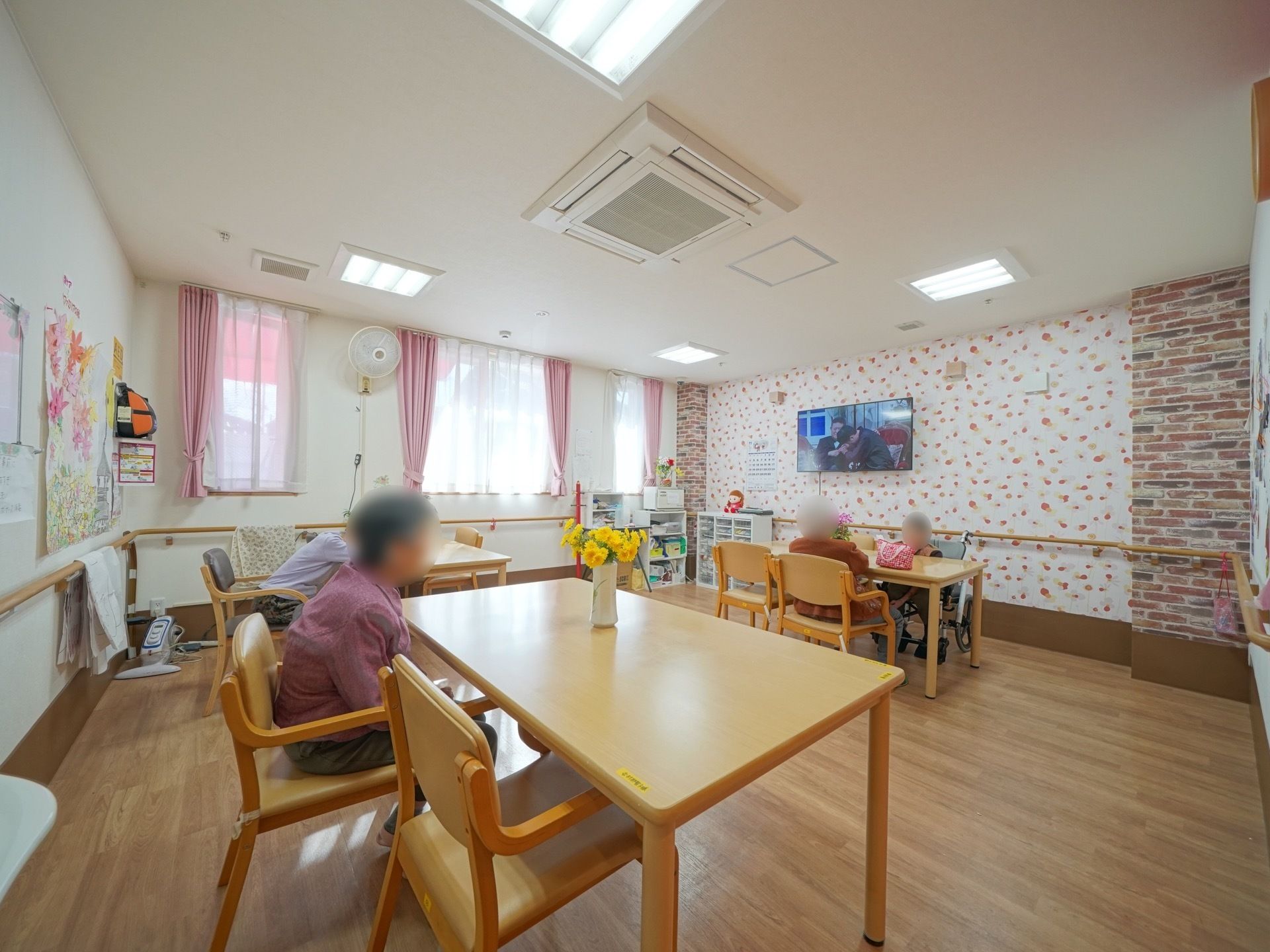 談話室にはエアコンと扇風機が完備されており、入居者様の体温調節がしやすくなっている。机の上には花が飾られ、彩りが添えられている。
