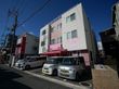 ピンク色を基調とした施設の外観である。施設前には駐車場が用意されており、来訪者様が自動車で訪問できるように配慮されている。