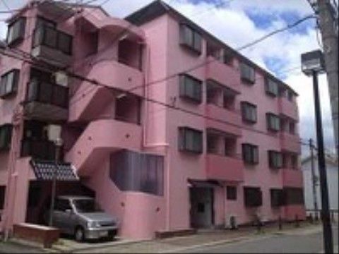 ピンクの外壁が印象的な、ベランダ付き４階建ての施設外観