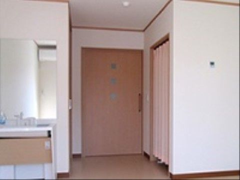 大きな居室の扉が見える。入口近くに洗面台が設けられていて、大きな鏡が掛けられている。水栓はシングルレバータイプである。