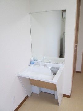 大きな鏡が掛けられている。洗面台の下は傾斜がついており、足を入れることができるので車椅子をご利用の方でも使いやすくなっている。