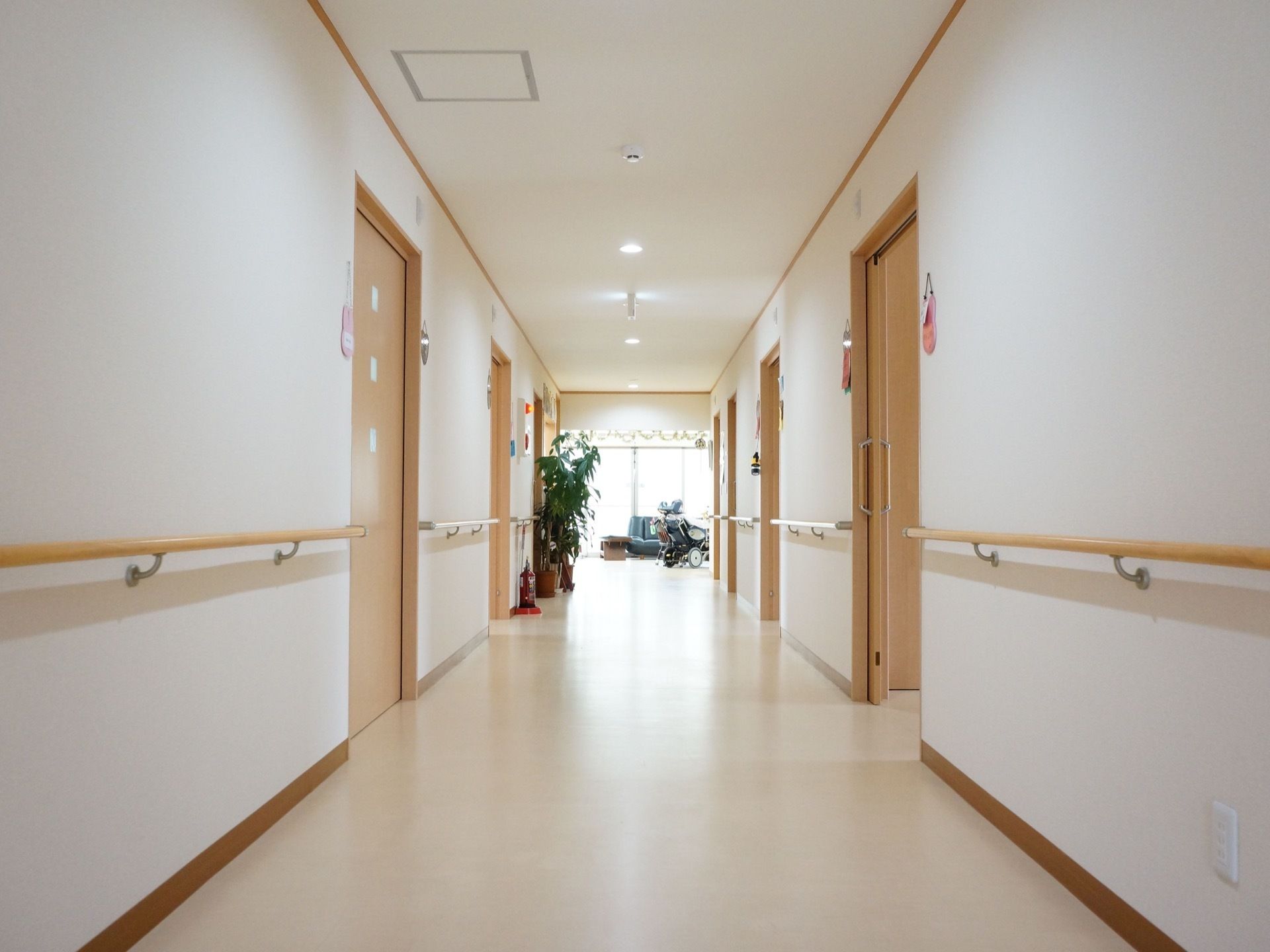 通路の壁は白く、床・建具にはナチュラル系の色が使われている。居室のドアはスライド式で大きい。充分な幅が取られている。