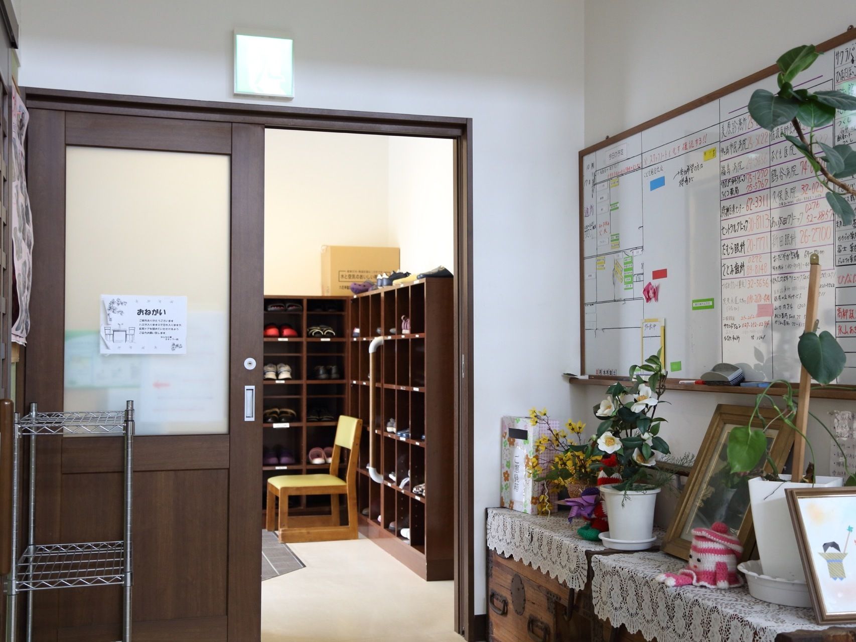 玄関にある靴箱には手すりが取り付けられている。その近くには、椅子も置かれている。手前にある部屋の壁にはホワイトボードがある。