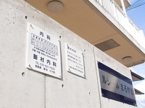 内科の案内や施設名が書かれた看板の貼られたコンクリートの壁