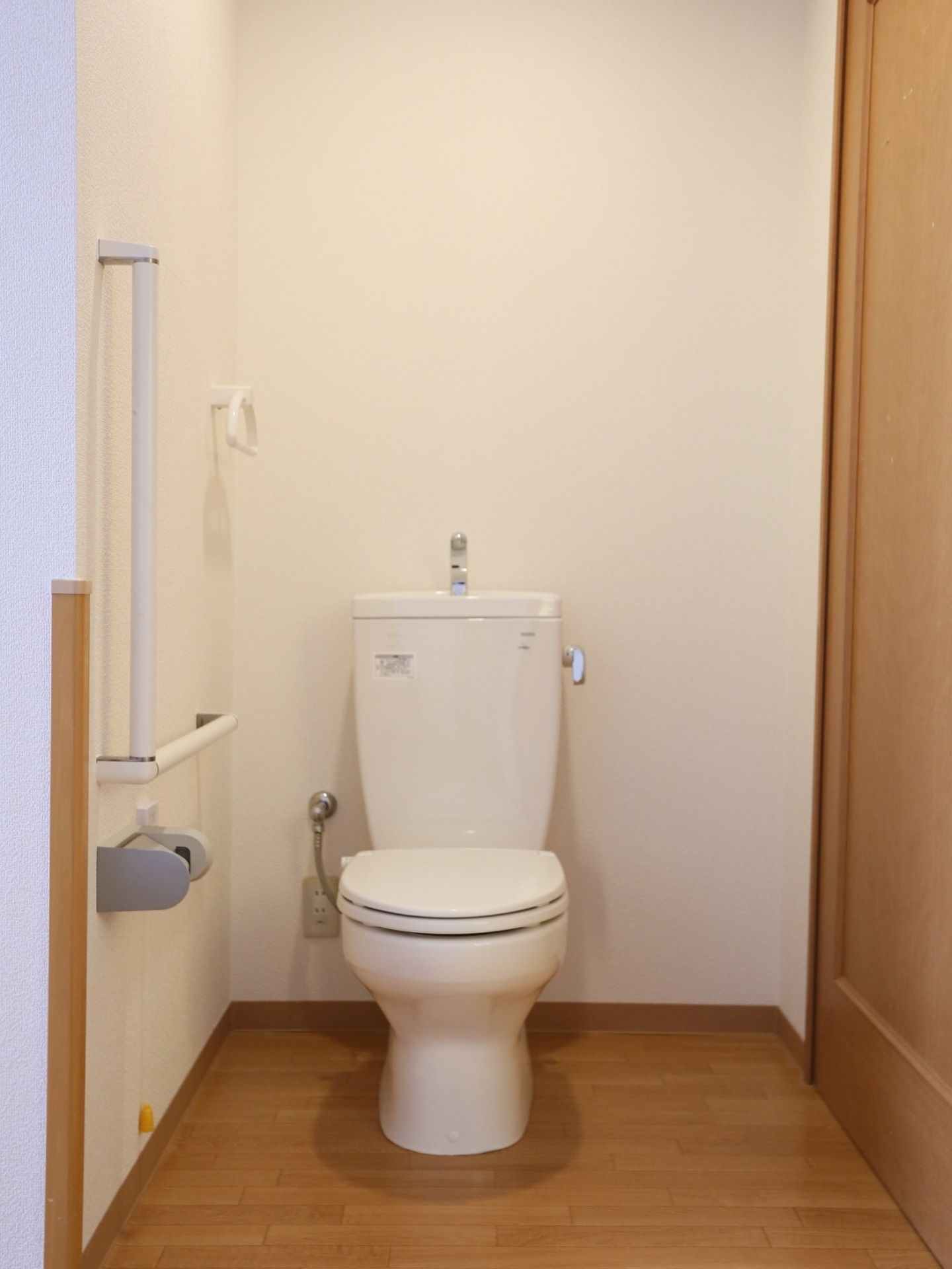 白い便座器が完備されたトイレは、清潔感があり衛生的である。Ｌ字型手すりや緊急ブザーが設置されている。
