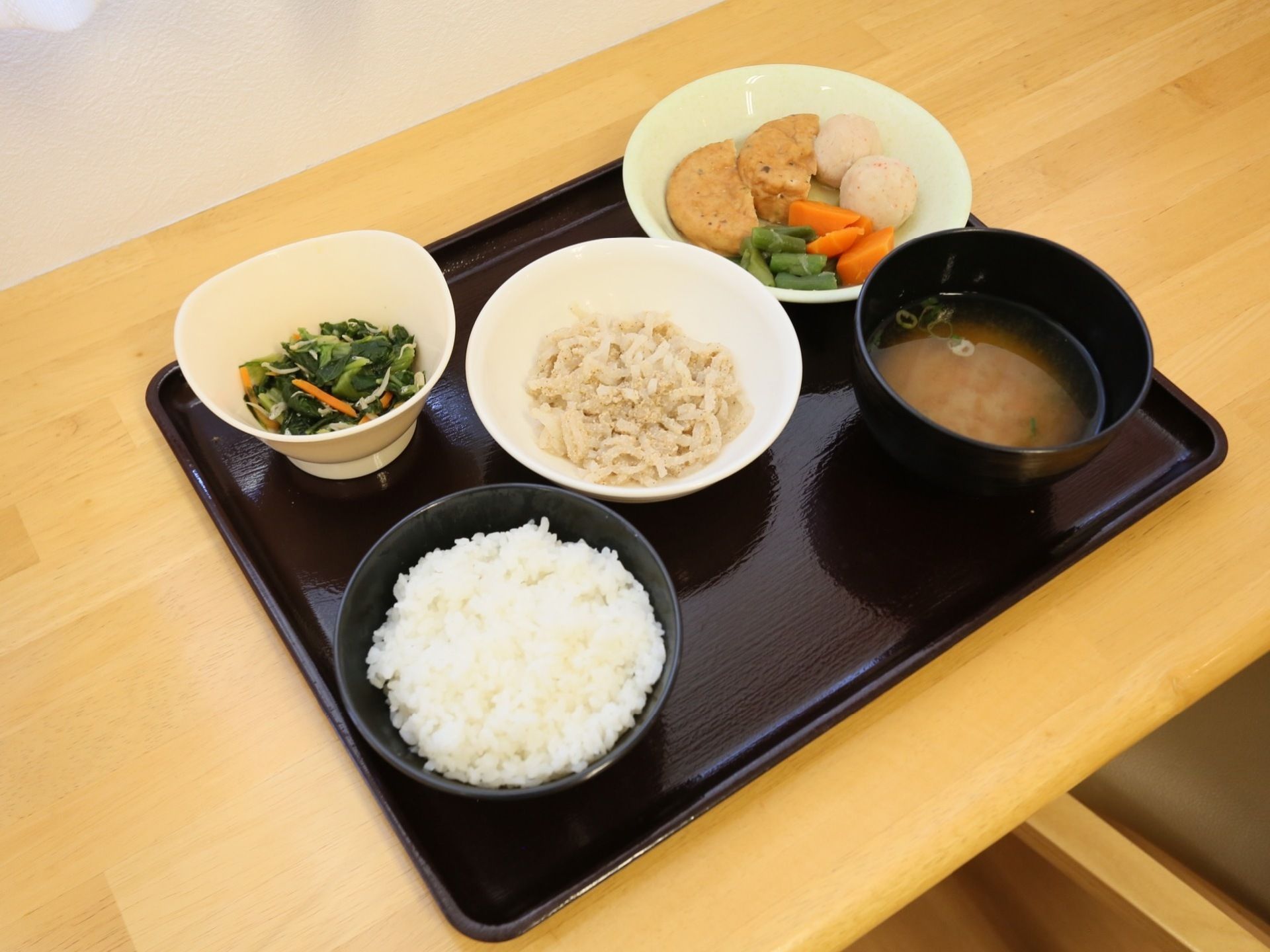 栄養バランスや盛りつけが考慮された一汁三菜の食事メニューである。黒いプレートに並べられ入居者様に配膳される。