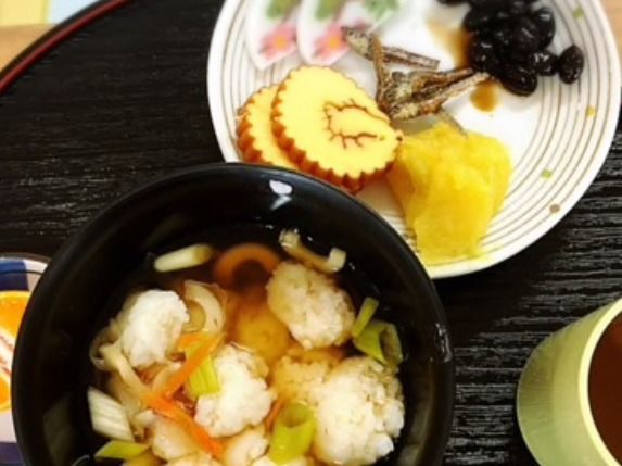 黒いお盆に乗った、だし巻きや黒豆といった縁起物の料理