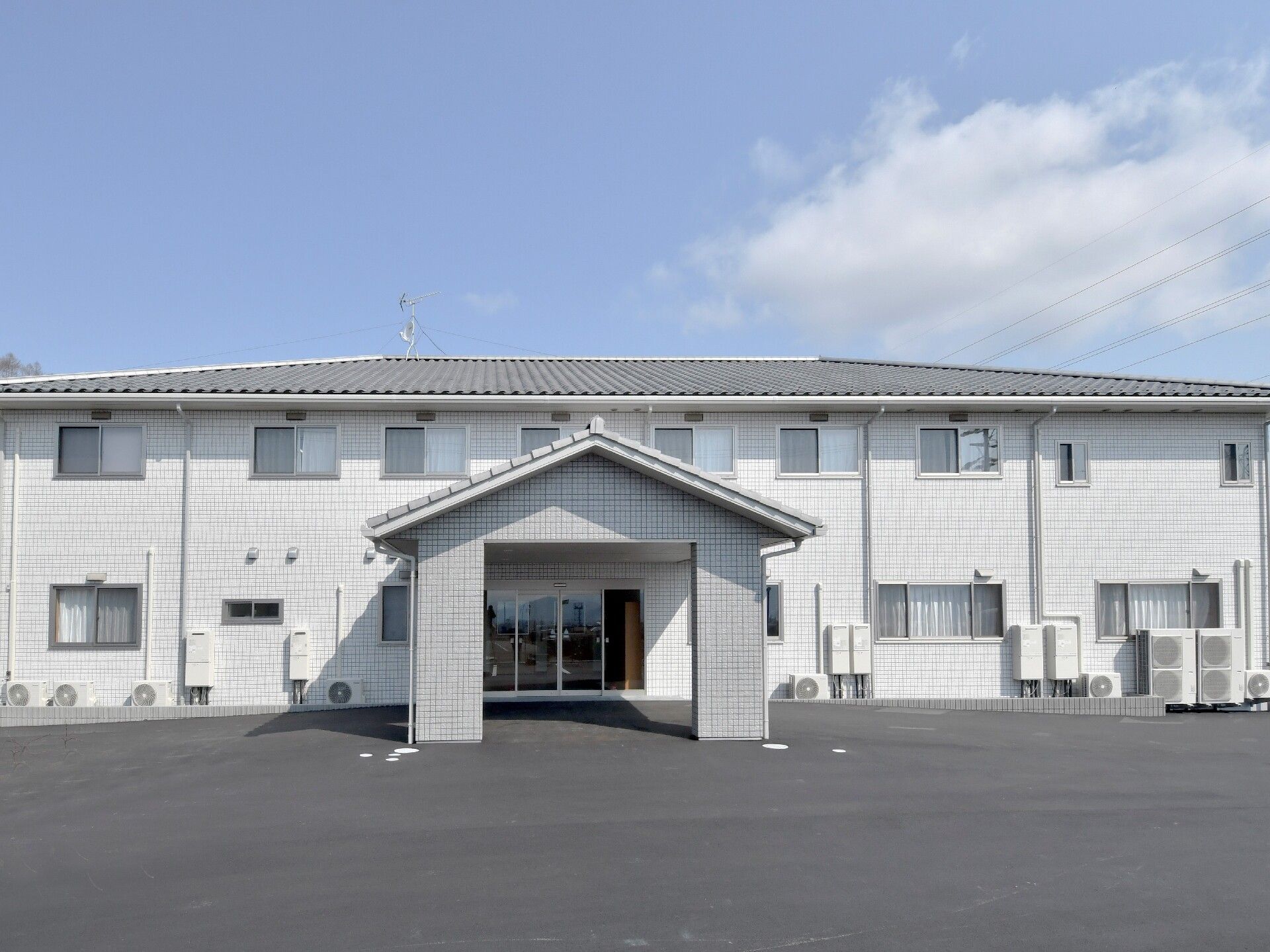 広々とした敷地内に建てられた玄関前に屋根のかかる2階建ての建物