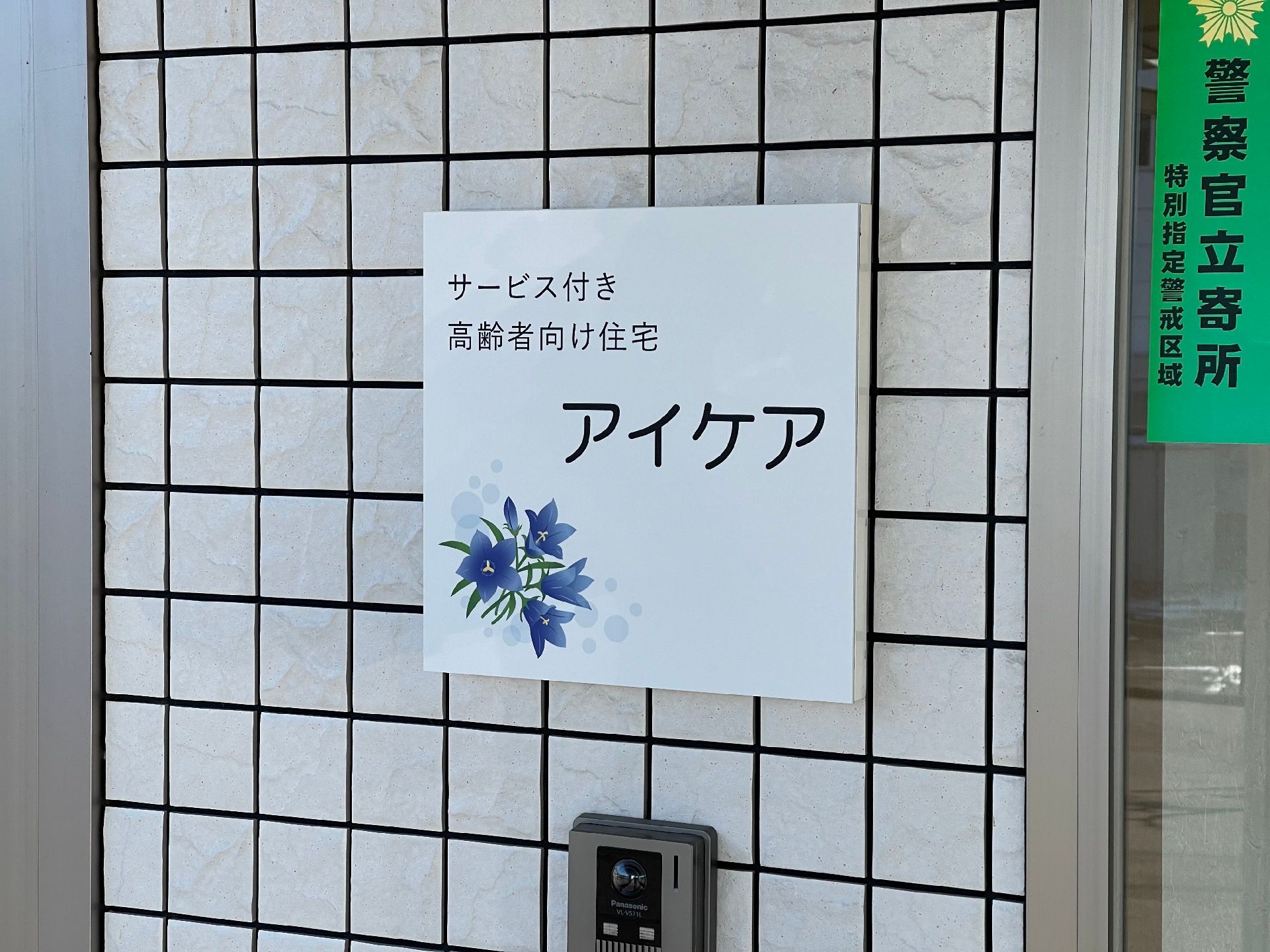 敷地の出入り口には、施設名が記された看板が設置されている。モニター付きのインターホンが用意されている。
