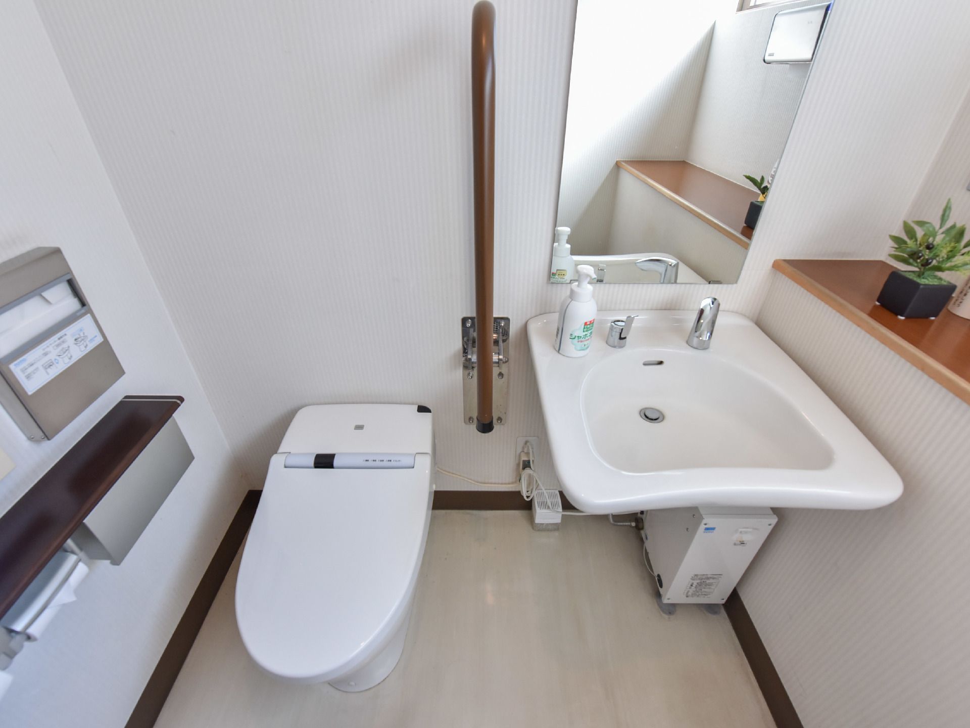 便座の横には手すりが設置されており、スムーズに洗面台に移動することができる。トイレットペーパーの他にペーパータオルも設置されている。