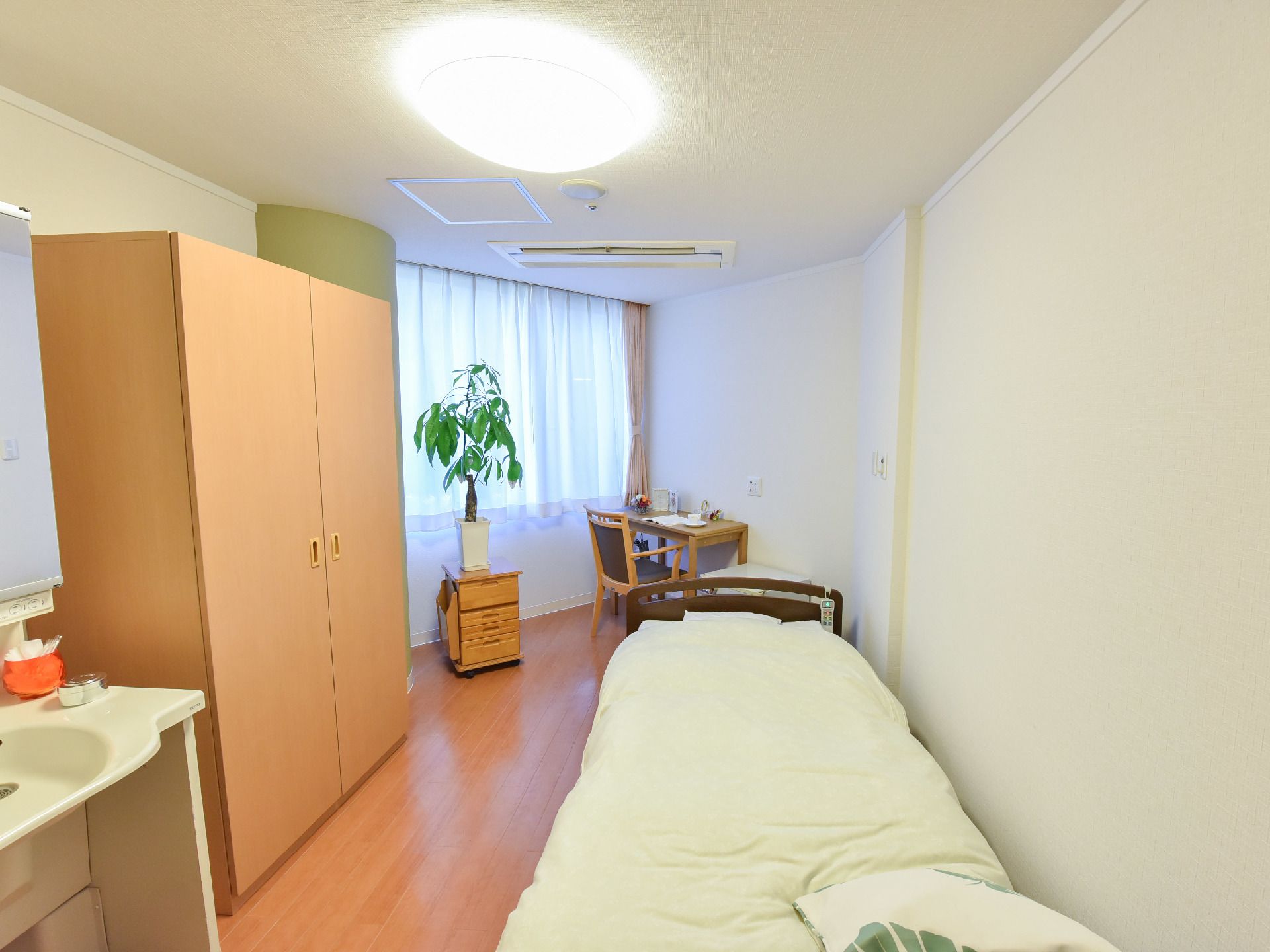 居室には大きな窓があり、横には机と椅子が備え付けられている。ベッドの近くには洗面台があり、収納も備えられている。