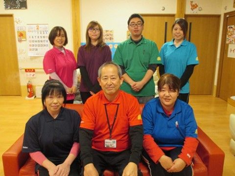 室内の一角でユニフォームを着て2列に整列する施設職員たち