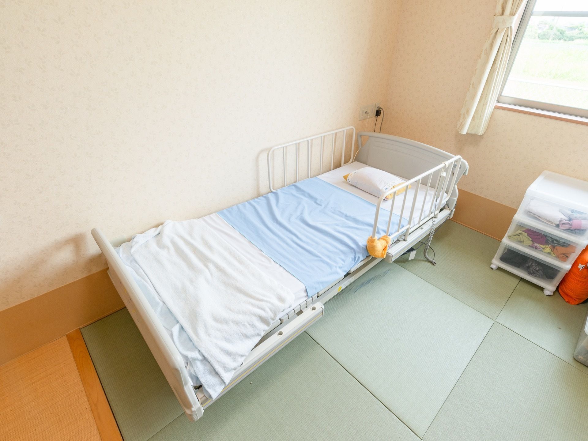 畳敷きの床には介護ベッドが置かれており、横の壁にナースコールが設置されている。外の景色を望める窓が設けられている。