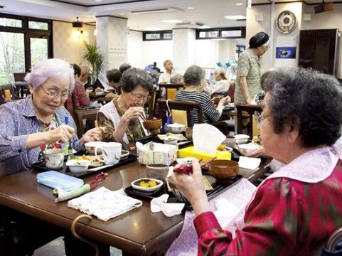 ダイニングテーブルを囲み、入居者と一緒に食事を楽しむ高齢者たち