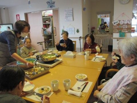 テーブルを囲み、鍋料理を楽しんでいる複数名の入居者